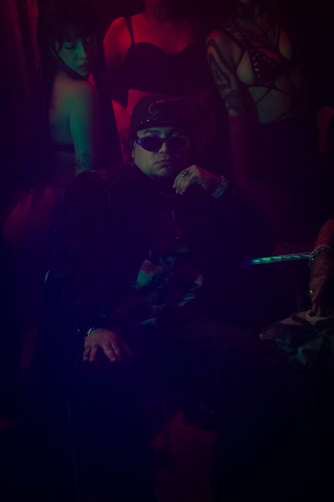 Danivlezz sentado en el club, luz roja y verde, escena nocturna